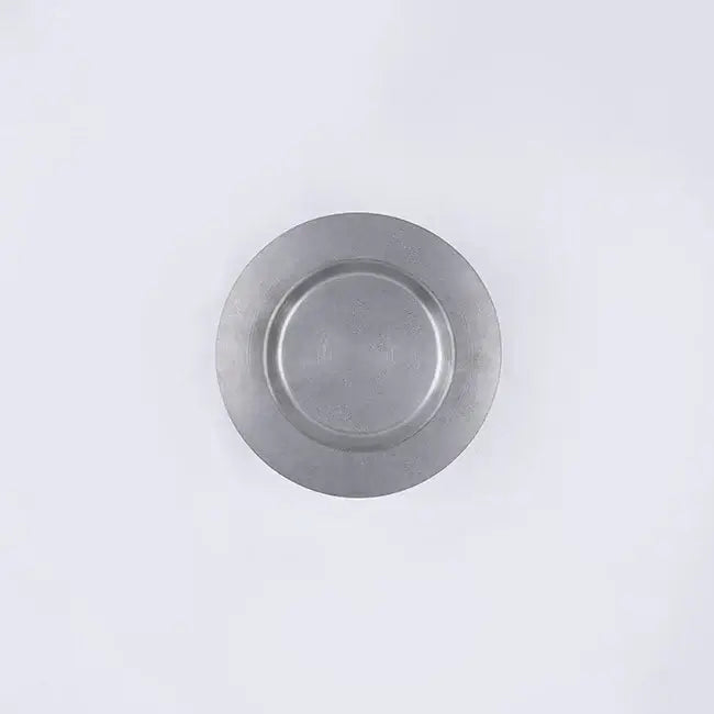 Stainless steel round plate with a chocolate dessert and fork on a dark table.
