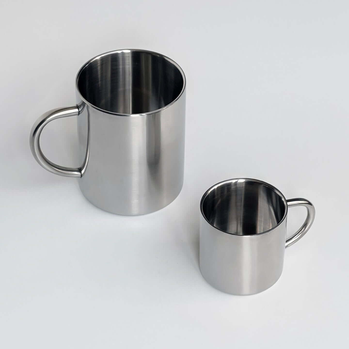 Double-layer glossy stainless steel cups on a marble surface, ideal for keeping beverages at the perfect temperature.