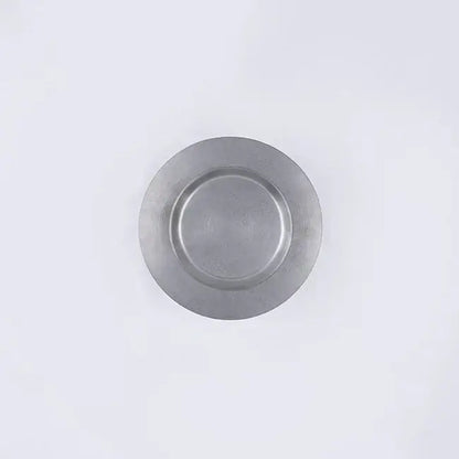 Stainless steel round plate with a chocolate dessert and fork on a dark table.
