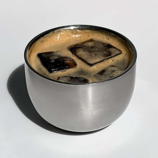 Stainless steel spherical cup with iced coffee inside, showcasing elegant design and double-walled insulation.