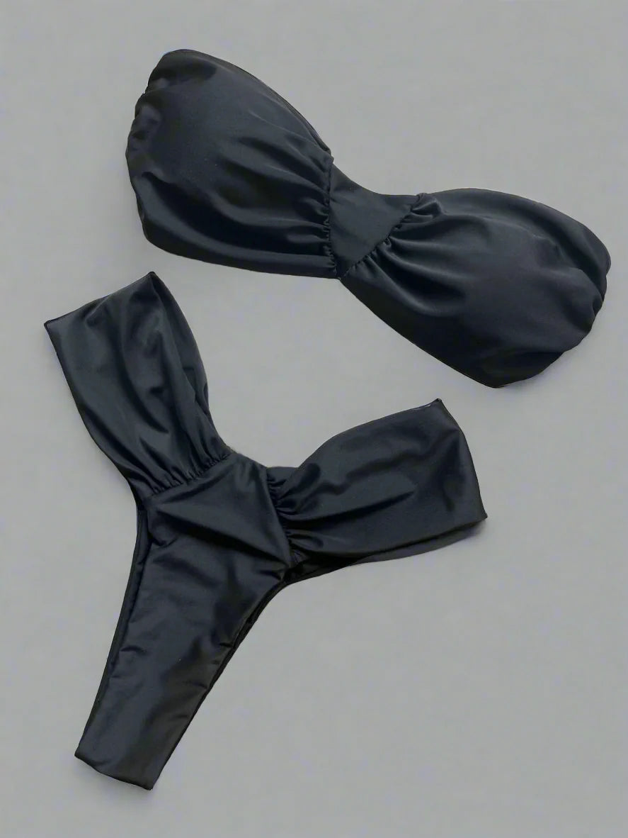 Black bikini set on a textured surface with a woven mat