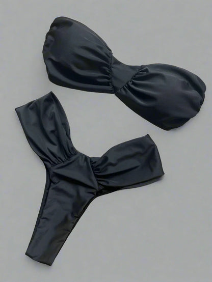 Black bikini set on a textured surface with a woven mat