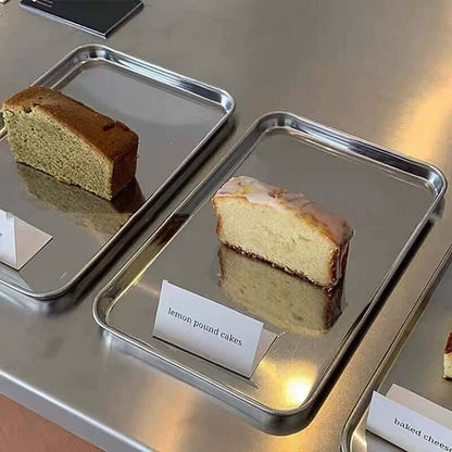Minimalist stainless steel tray with iced coffee, matcha latte, and dessert at a modern café.