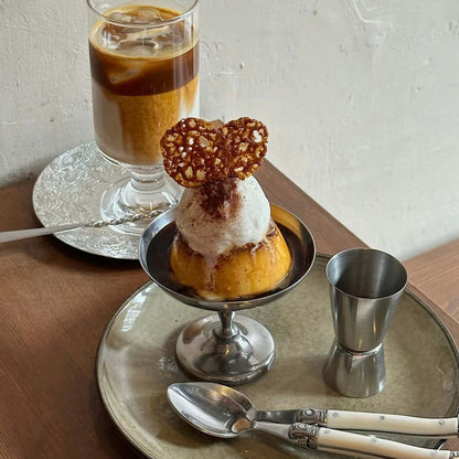 Elegant dessert displayed on a polished stainless steel cup with artistic garnish, set atop a matching tray.