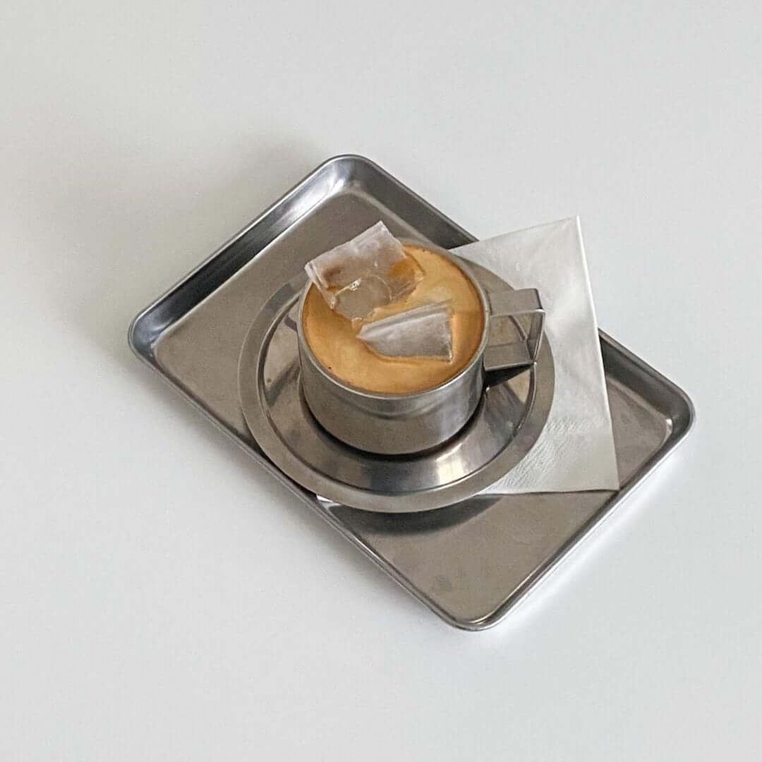 Stainless steel tray with coffee, waffles, and ice cream, showcasing minimalist design and elegance.