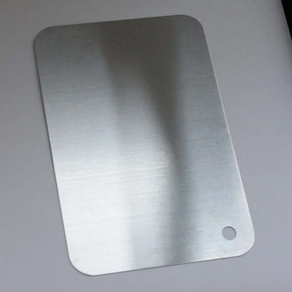 Minimalist stainless steel cutting board used as serving platter with cheese, crackers, and spread on wooden table.
