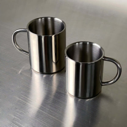 Double-layer glossy stainless steel cups on metallic surface, modern elegance, perfect for temperature control and any occasion.