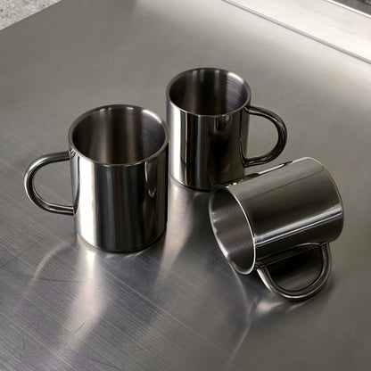 Double-layer glossy stainless steel cups on metallic surface, modern elegance, perfect for temperature control and any occasion.